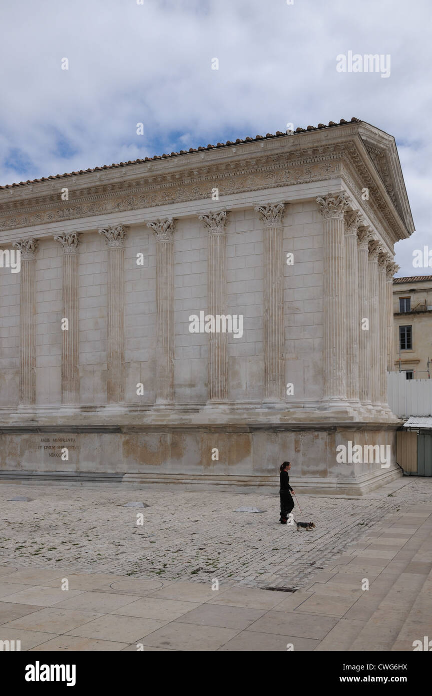 Maison Carree Tempio romano o Piazza casa costruita sotto Augusto verso la fine del I secolo a.c. in Nimes Francia con la donna e cane Foto Stock