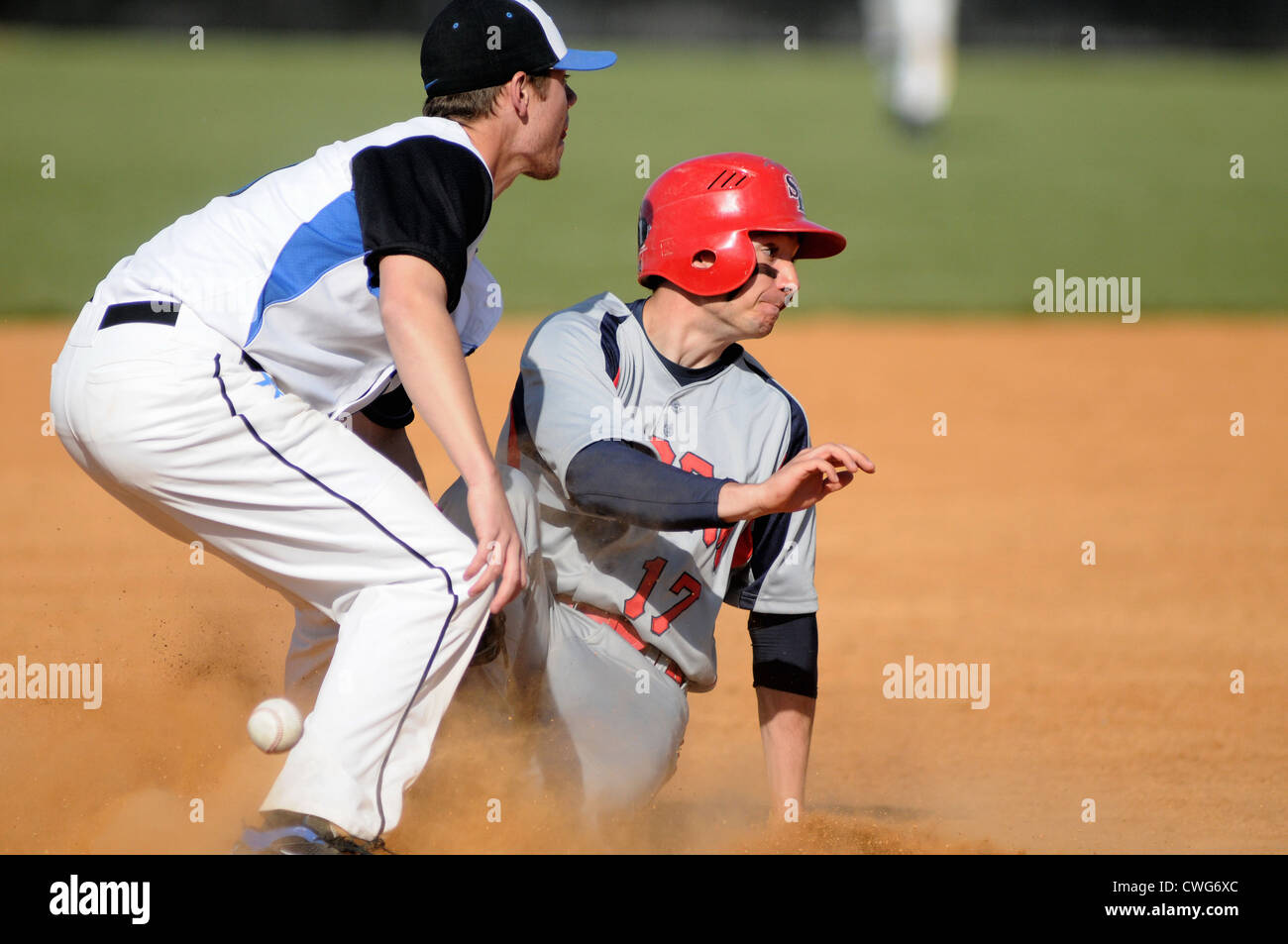 Base di baseball runner scorre in modo sicuro in terza con il terzo baseman tenta di effettuare un tag durante una scuola di gioco. Foto Stock