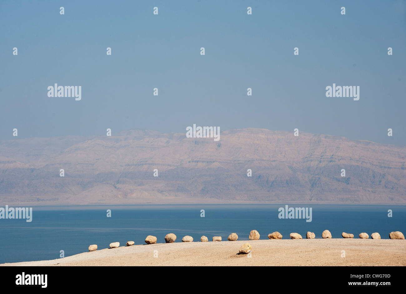 Una vista del Mar Morto con un bordo di roccia di piccole dimensioni in primo piano e le montagne della Giordania nella distanza, Israele Foto Stock