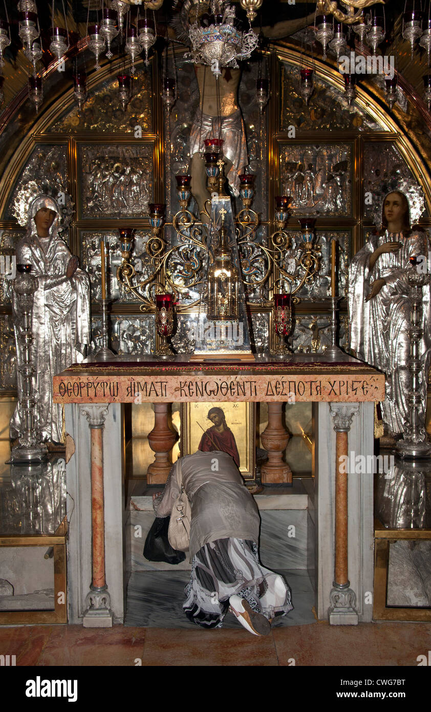 Una donna che prega nel luogo in cui Gesù Cristo è stato creduto di essere stato crocifisso, la Chiesa del Santo Sepolcro di Gerusalemme Foto Stock