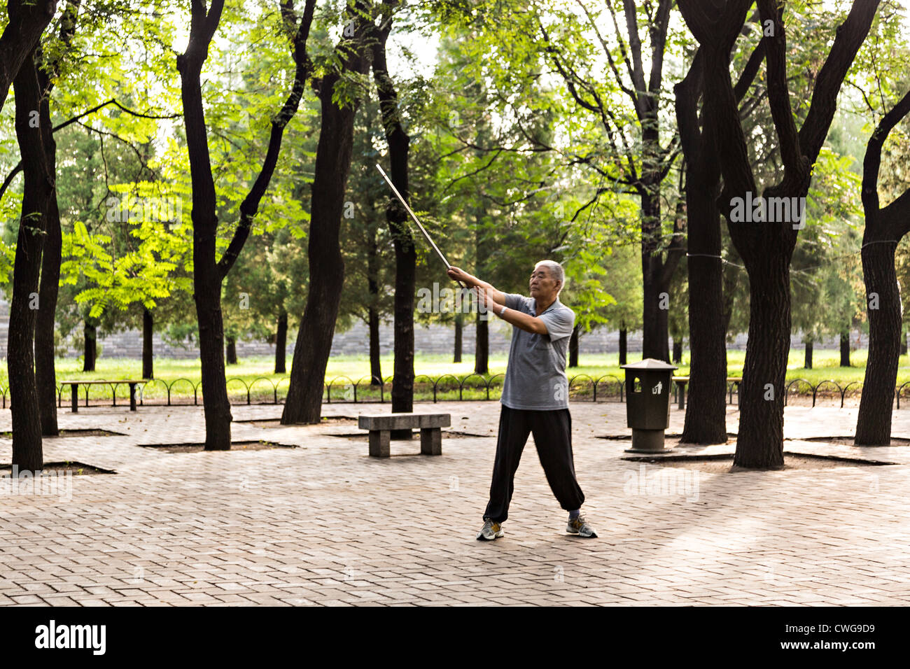 Un anziano uomo cinese pratica le arti marziali con la sua canna da zucchero passeggiata mattutina presso il Tempio del Paradiso Parco durante l'estate in bei Foto Stock