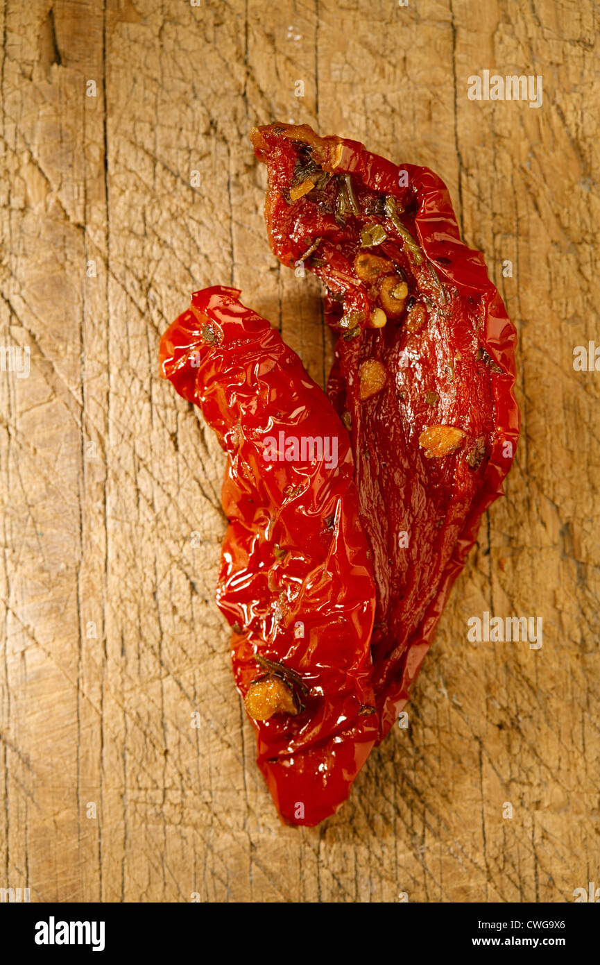 Due pezzi di pomodori essiccati sul vecchio sfondo di legno Foto Stock