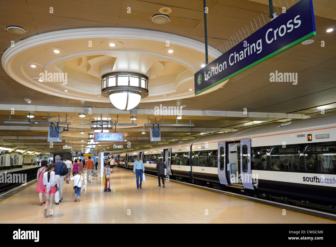 Passeggeri in famiglia e treno alla stazione ferroviaria di London Charing Cross Piattaforma con grande illuminazione ornamentale soffitto e segno Londra Inghilterra Regno Unito Foto Stock