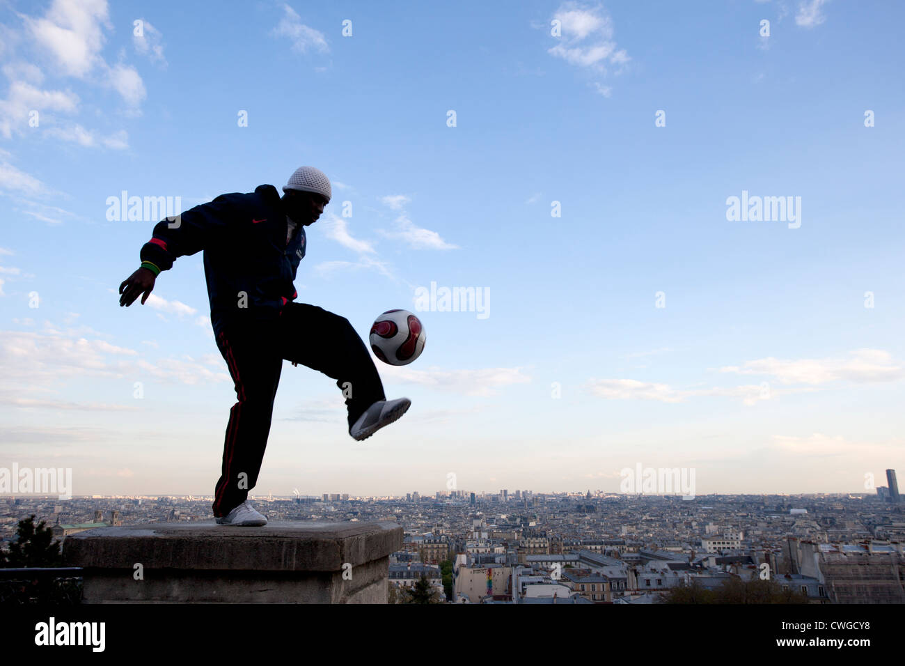 Un giovane uomo dimostra la sua abilità con un calcio sui gradini del Sacre Coeur, Parigi. Foto Stock