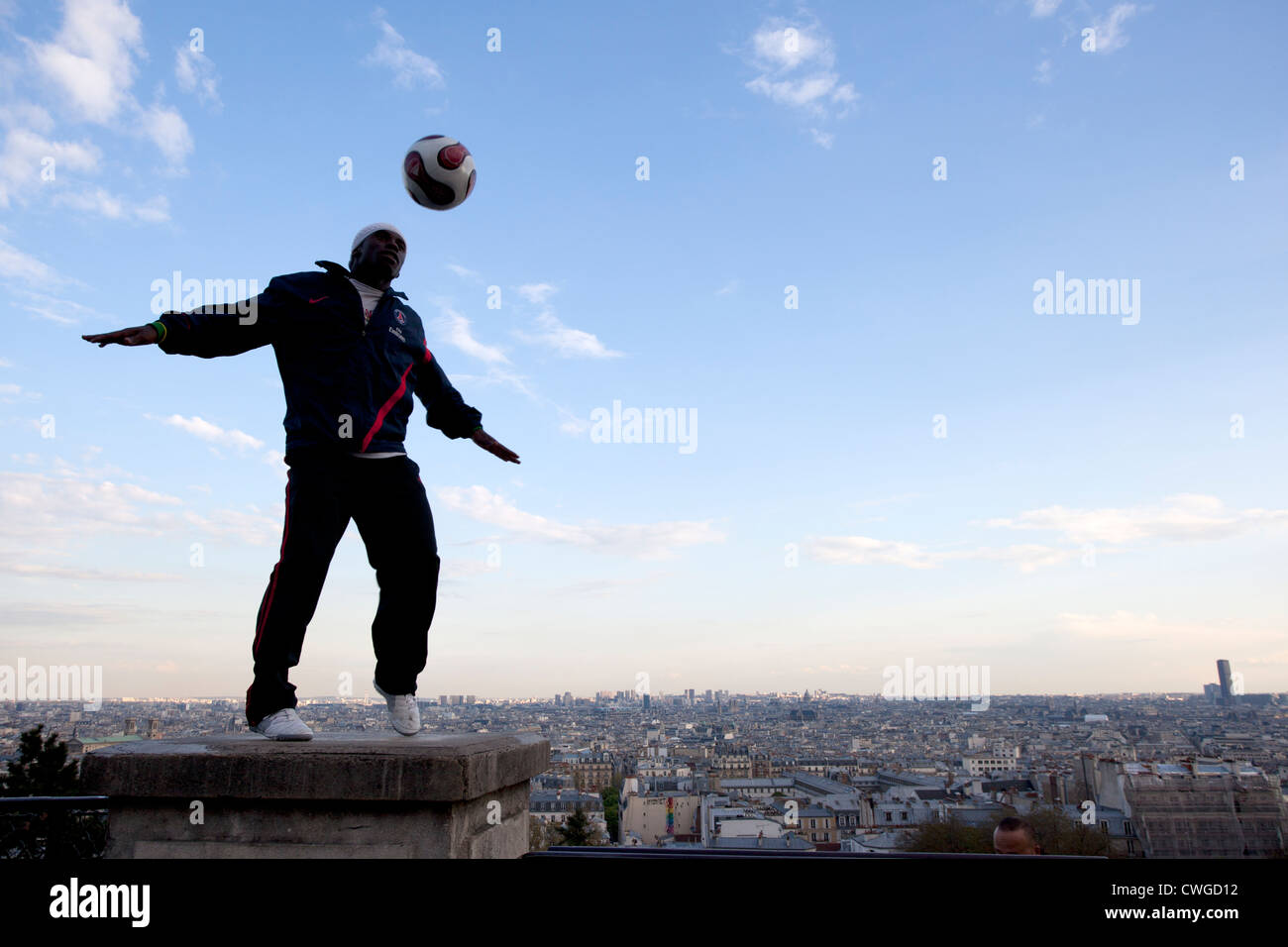 Un giovane uomo dimostra la sua abilità con un calcio sui gradini del Sacre Coeur, Parigi. Foto Stock