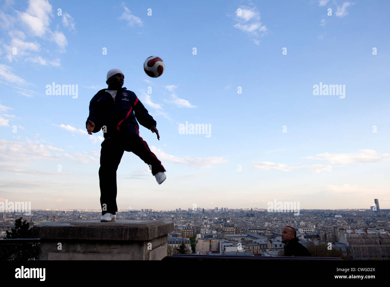 Un giovane uomo dimostra la sua abilità con un calcio sui gradini del Sacre Coeur, Parigi. Foto Stock
