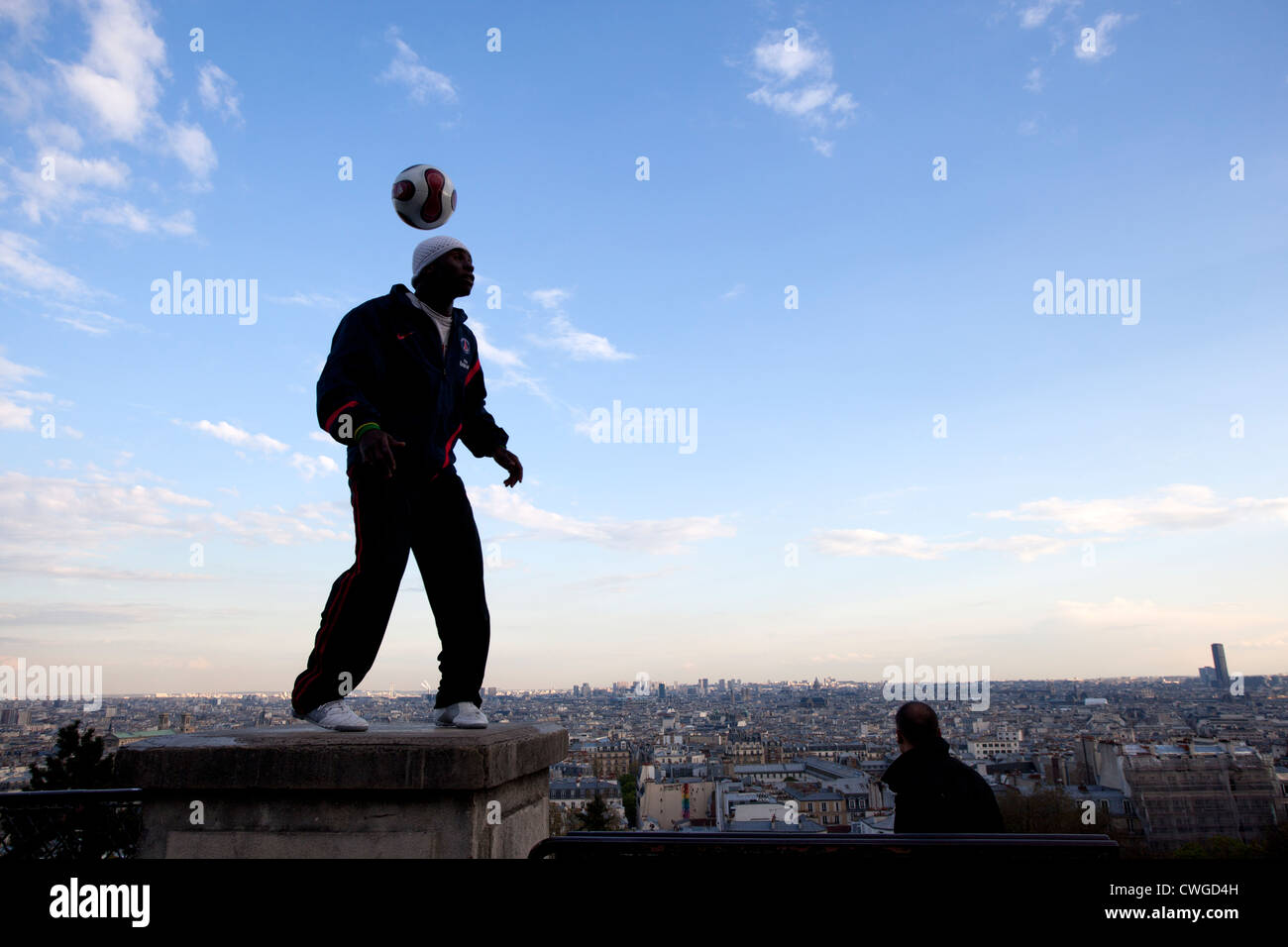 Un giovane uomo dimostra la sua abilità con un calcio sui gradini del Sacre Coeur, Parigi. Foto Stock