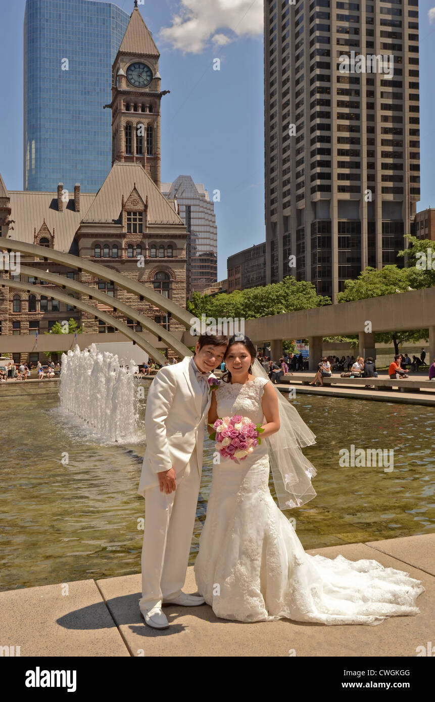 Sposi novelli sposi in posa di fronte delle fontane a Nathan Phillips Square, Toronto, Ontario, Canada. Foto Stock