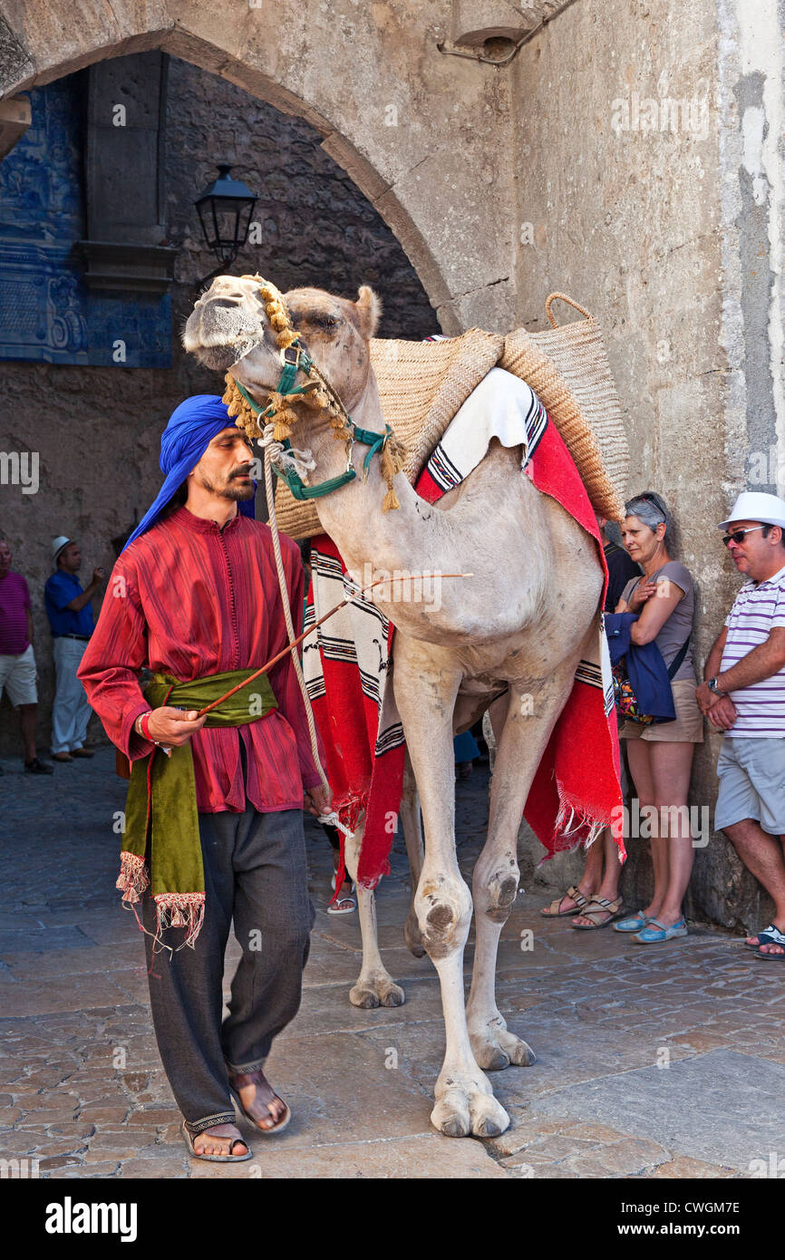 Uomo moresco con Cammello Dromedario in una rievocazione storica di una Fiera medievale in Óbidos, Portogallo. Foto Stock