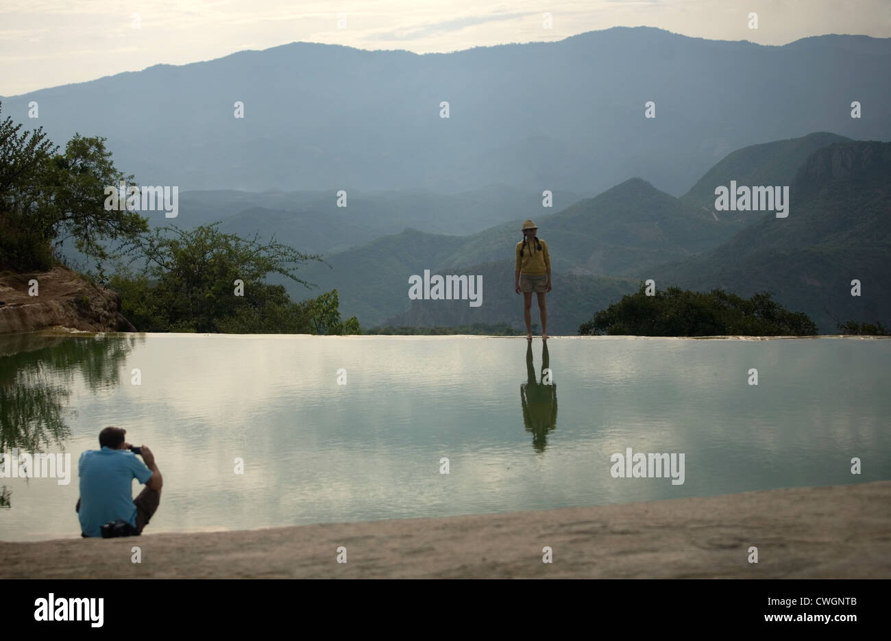 Un uomo prende una foto della sua fidanzata, che si riflette in una piscina naturale, di Hierve el Agua cascate pietrificate in Oaxaca, Messico Foto Stock