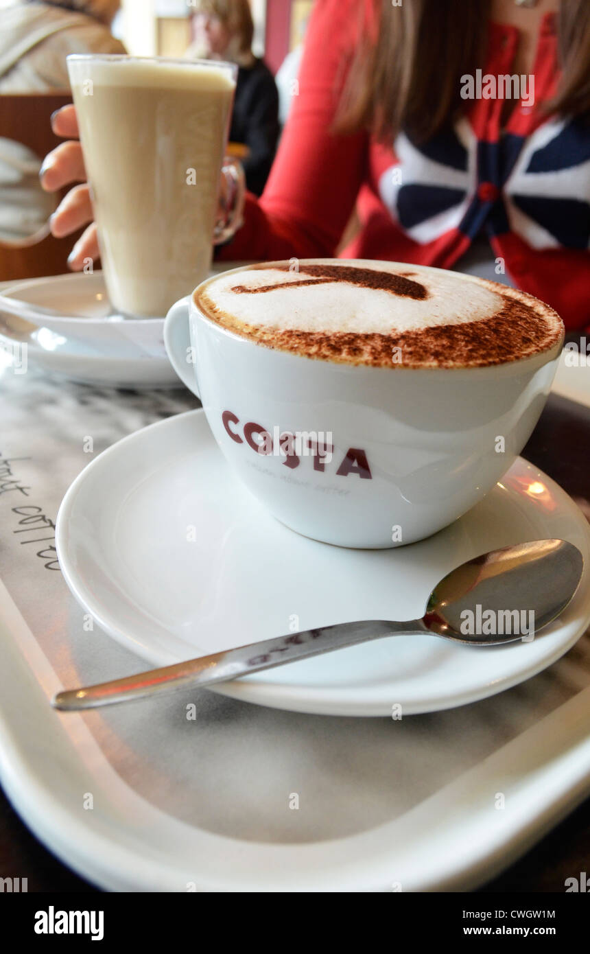 Raggiunge la ragazza per il suo latte nel caffè costa Foto Stock