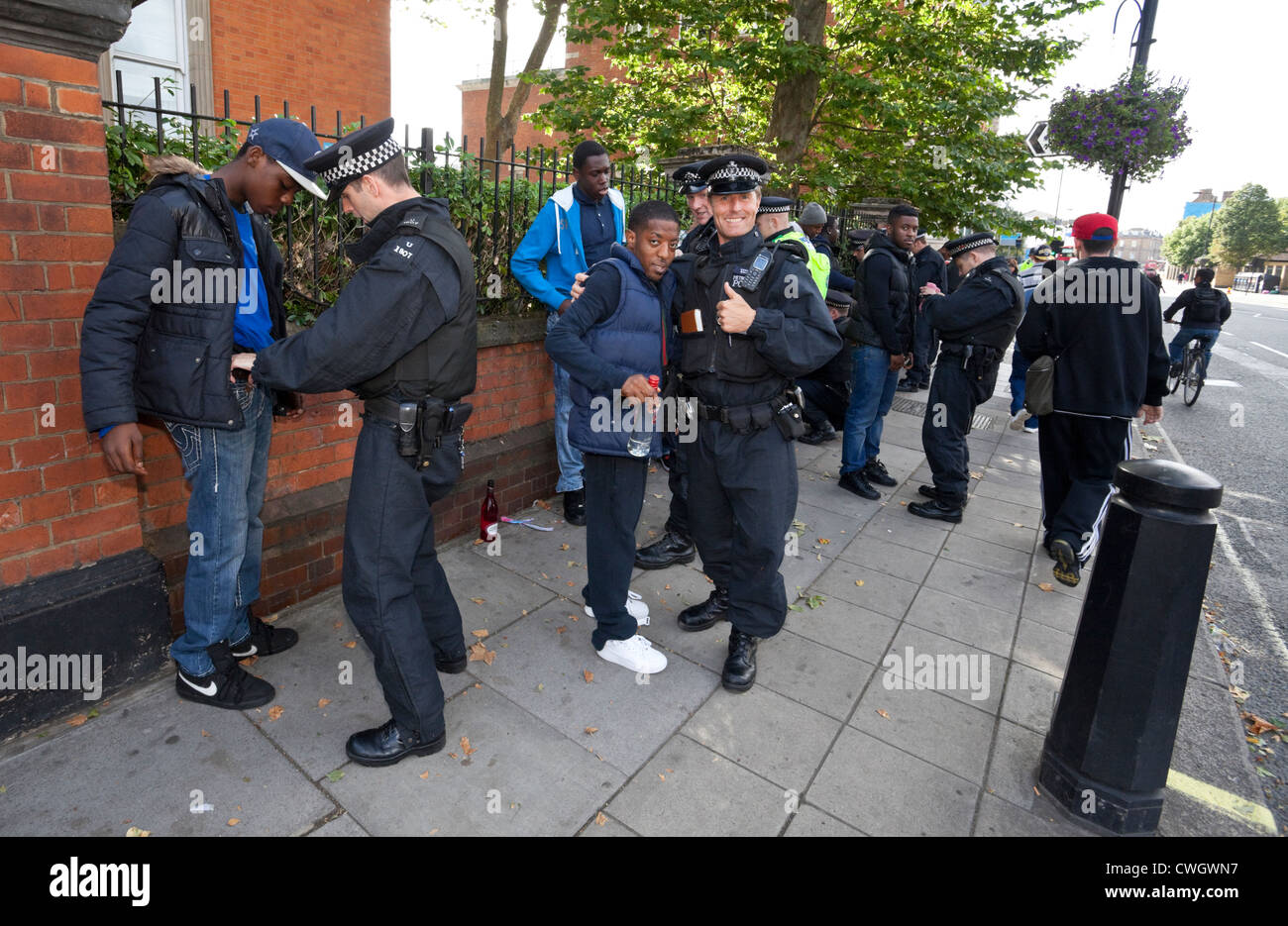 Gli agenti della polizia metropolitana fermano e cercano un gruppo di giovani neri al Notting Hill Carnival, Londra, Inghilterra, Regno Unito. Foto Stock