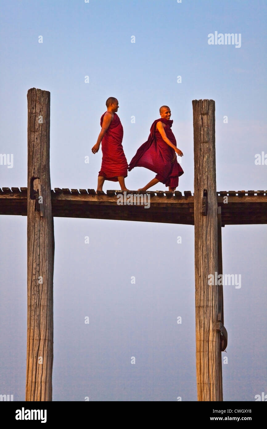 I MONACI BIRMANI utilizza il teak U BEINS ponte per commutare tra il Lago Taungthaman presso sunrise - AMARAPURA, MYANMAR Foto Stock