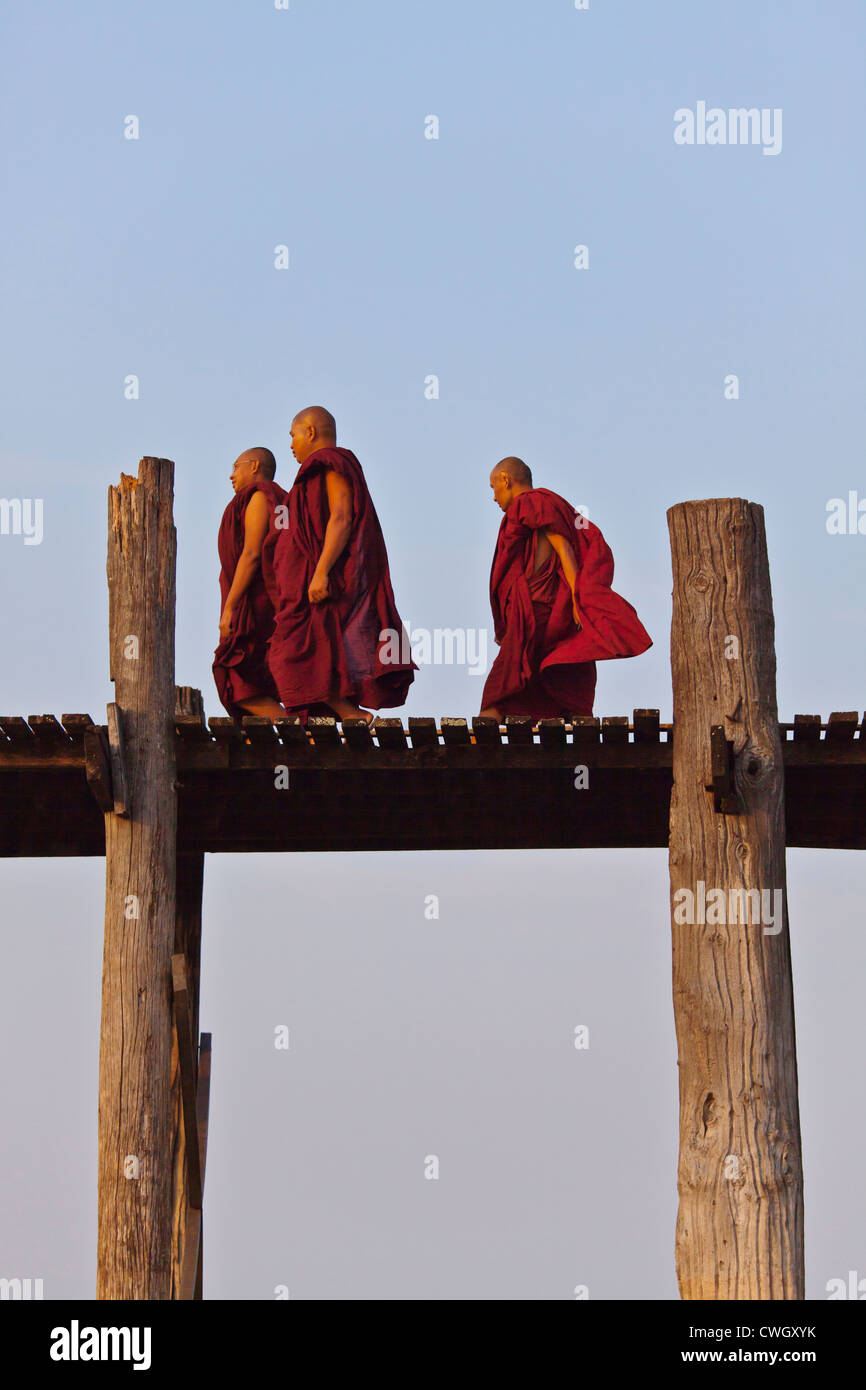 I MONACI BIRMANI utilizza il teak U BEINS ponte per commutare tra il Lago Taungthaman presso sunrise - AMARAPURA, MYANMAR Foto Stock