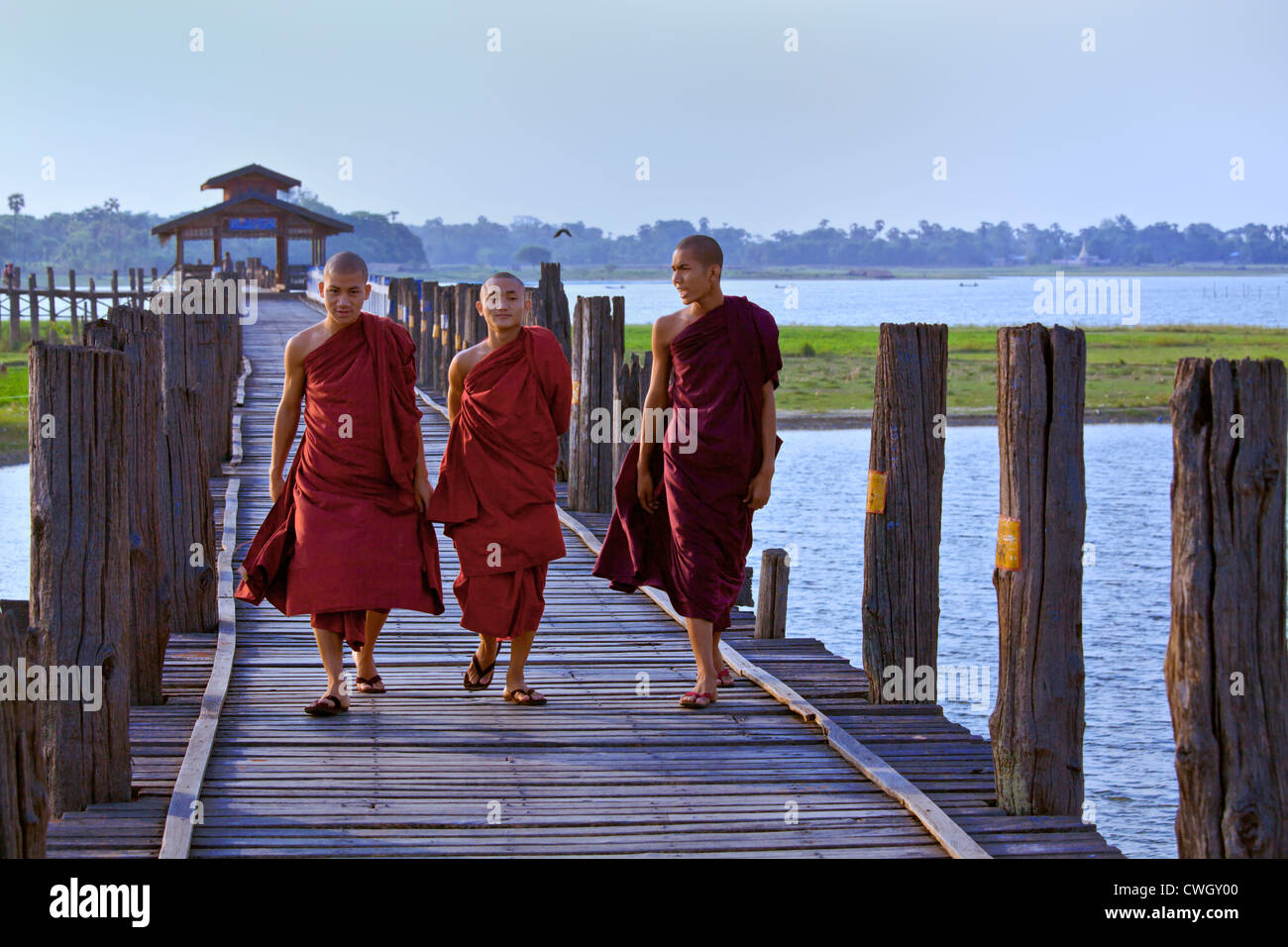 I MONACI BIRMANI utilizza il teak U BEINS ponte per commutare tra il Lago Taungthaman presso sunrise - AMARAPURA, MYANMAR Foto Stock