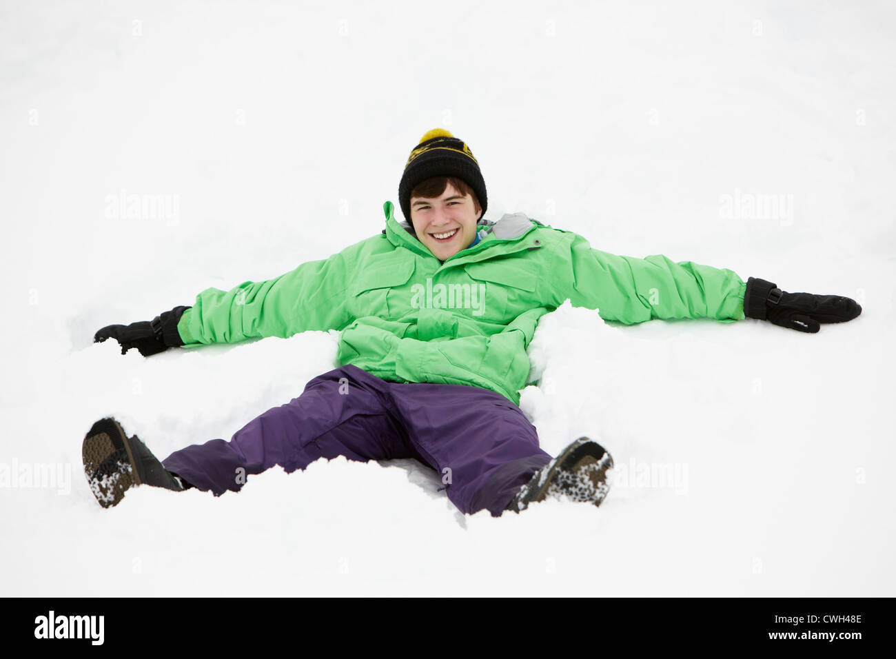 Ragazzo adolescente rendendo angelo di neve sul pendio Foto Stock