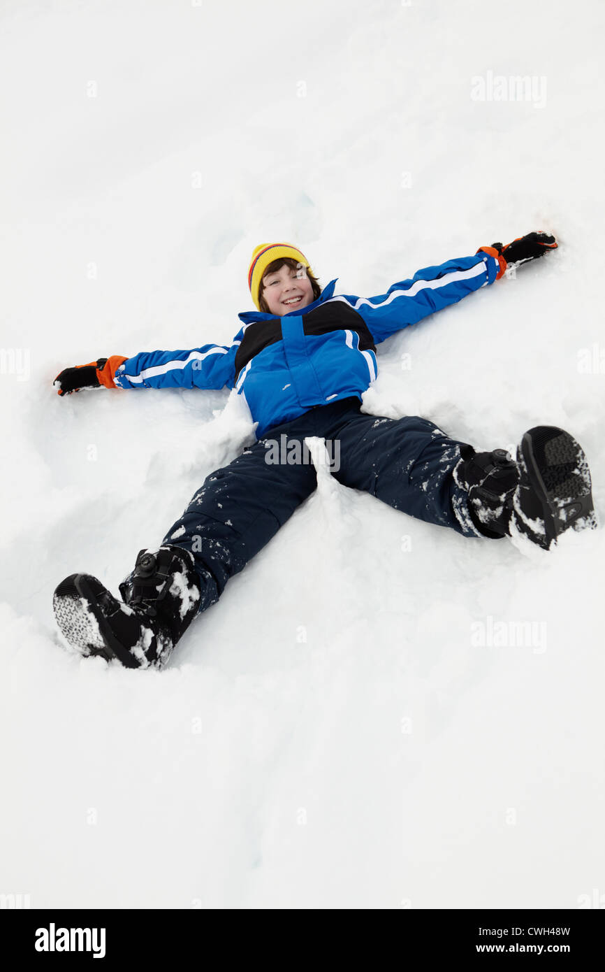 Ragazzo giovane rendendo angelo di neve sul pendio Foto Stock