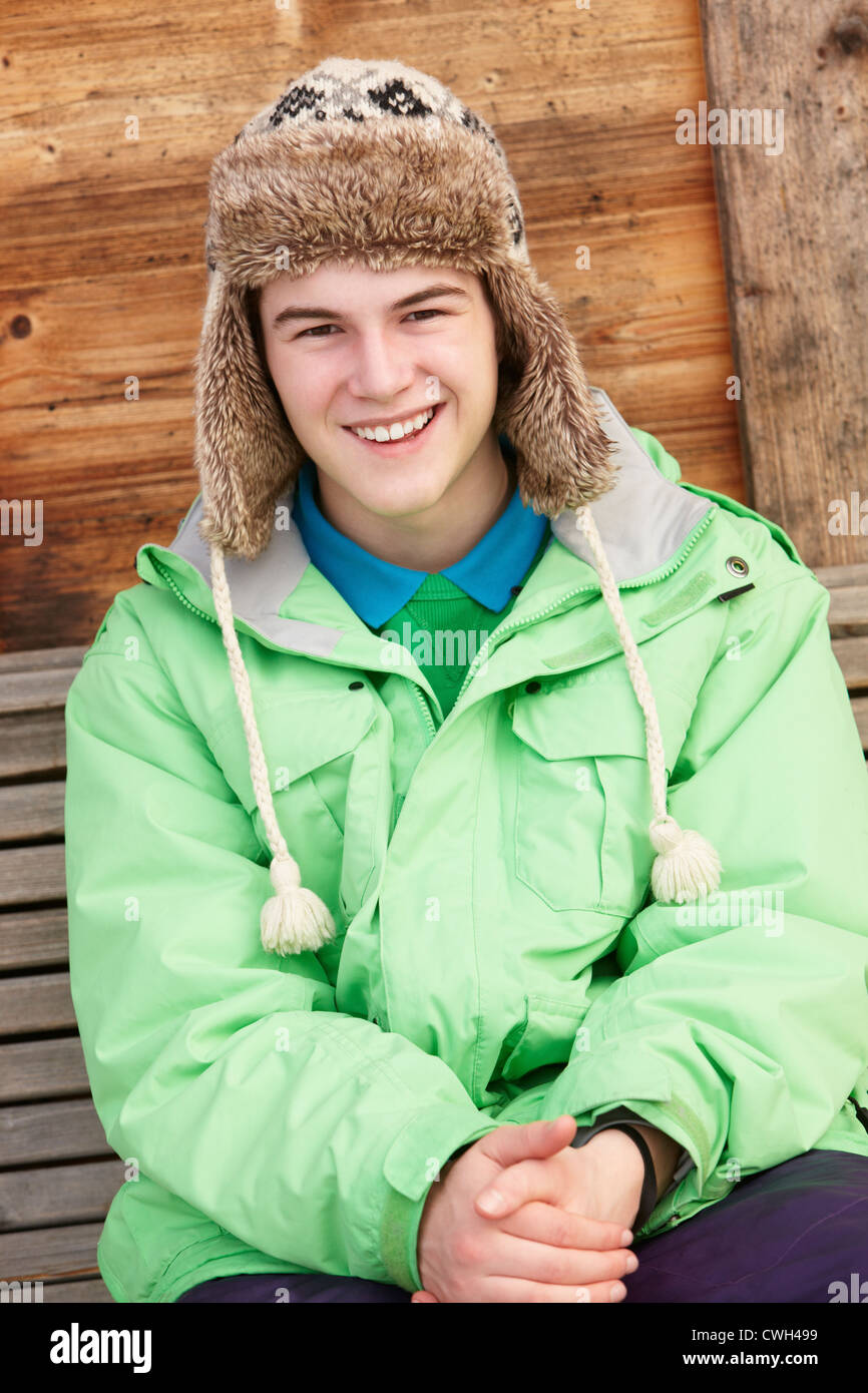 Ragazzo adolescente vestito per il Freddo seduti sulla panca in legno Foto Stock