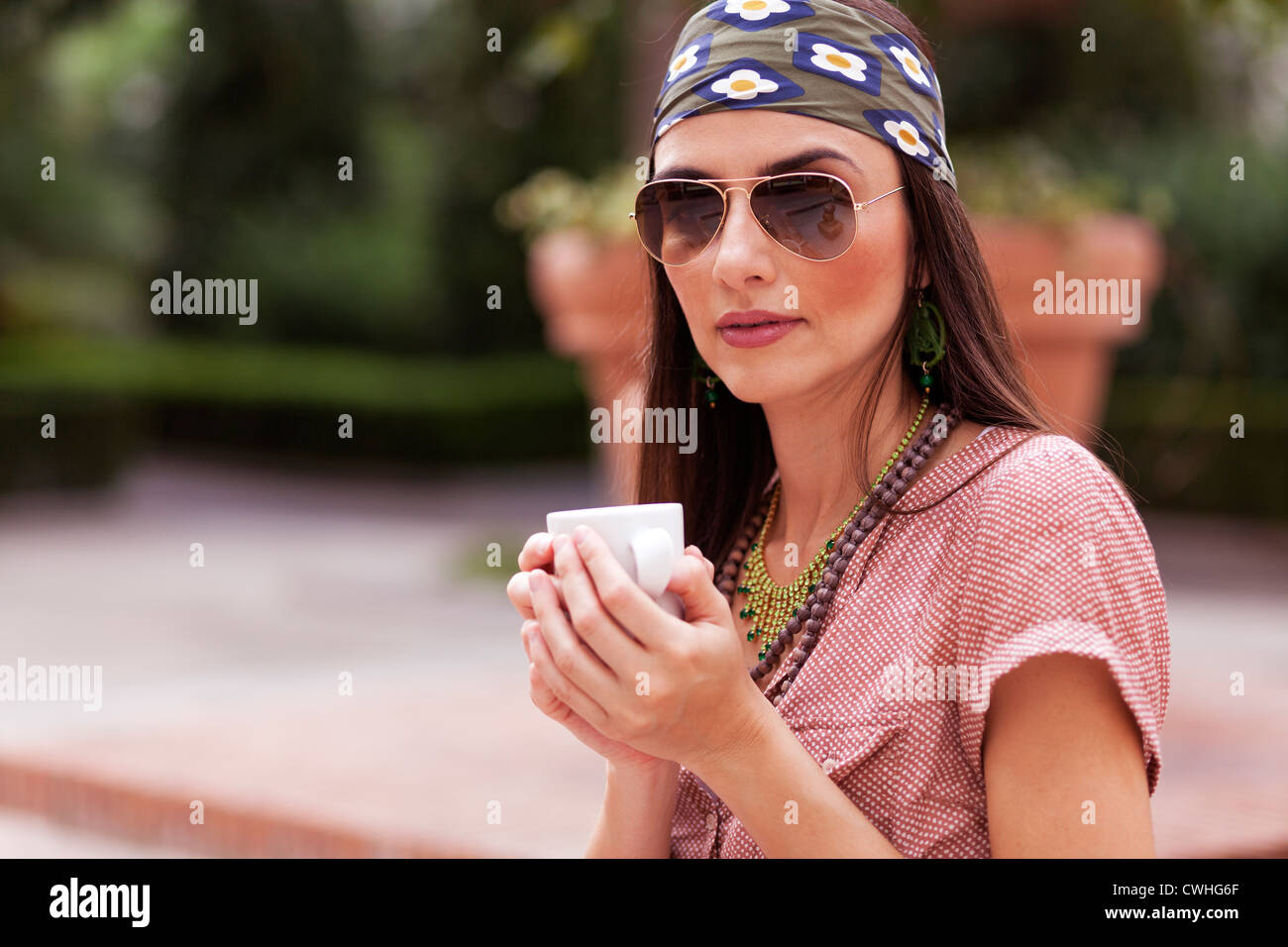 La donna a bere caffè e guardando la fotocamera Foto Stock