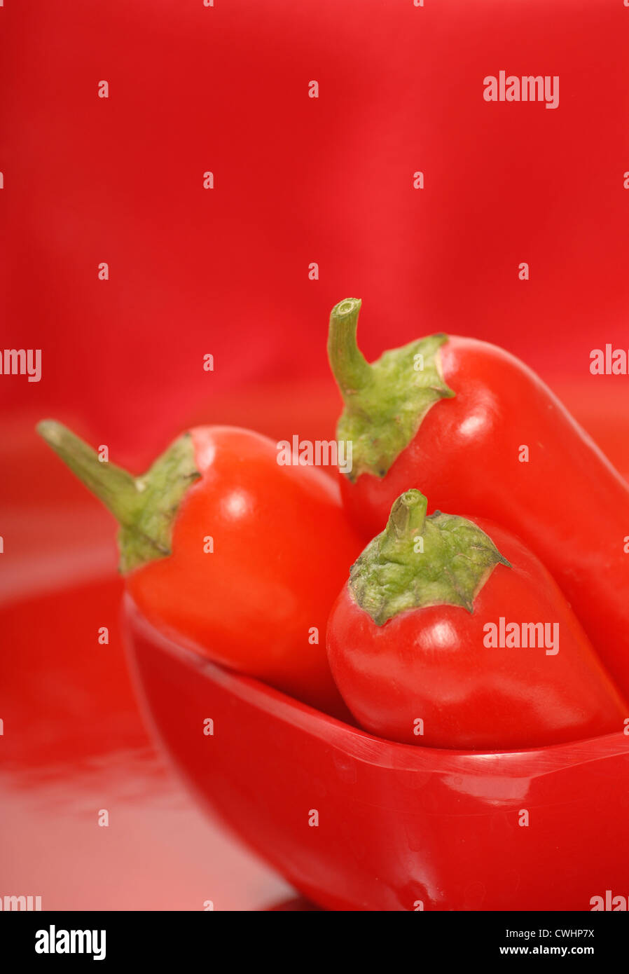 Peperoncino rosso in una vaschetta di colore rosso con uno sfondo rosso Foto Stock