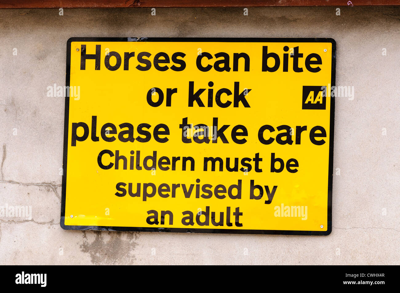 AA strada segno attenzione che i cavalli possono cacciare e mordere e consigliare i bambini devono essere accompagnati (mis-spelta come "bambini") Foto Stock