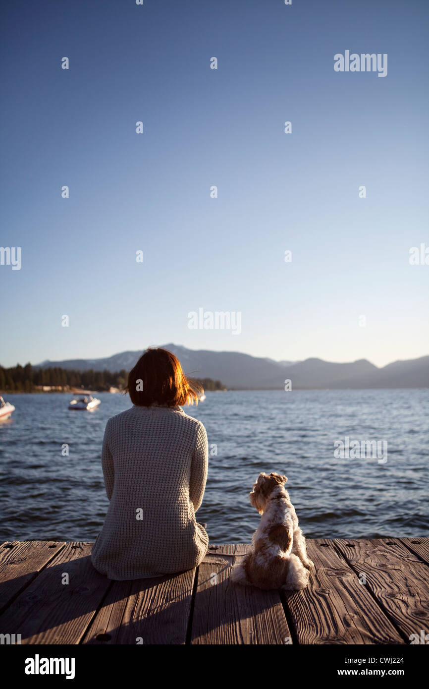 Donna e miniatura schnauzer seduta sul molo Foto Stock