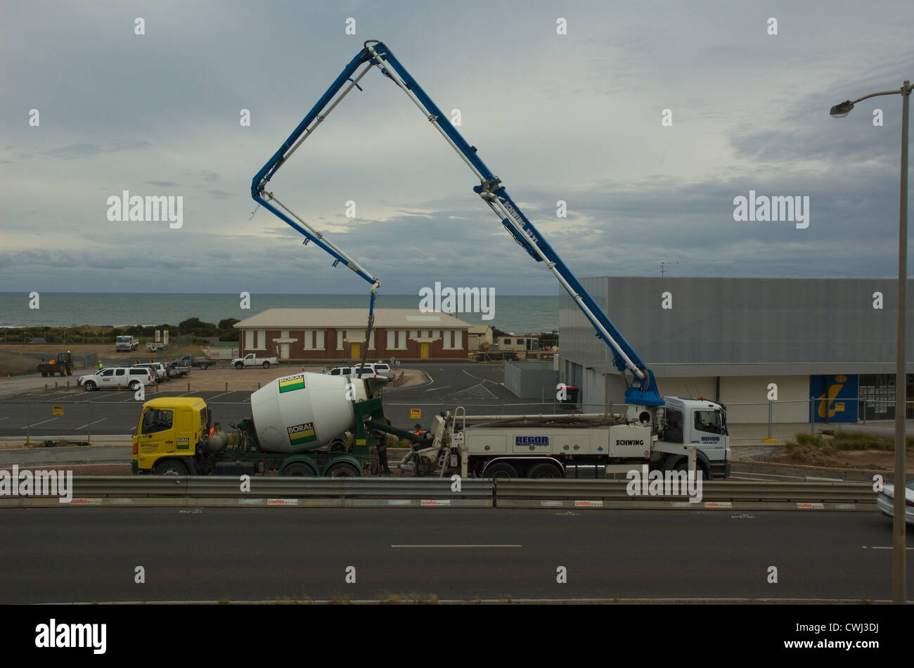 Calcestruzzo pompa braccio carrello recante una pista ciclabile, modello Schwing 32XL, e Boral betoniera. Burnie, la Tasmania. Foto Stock