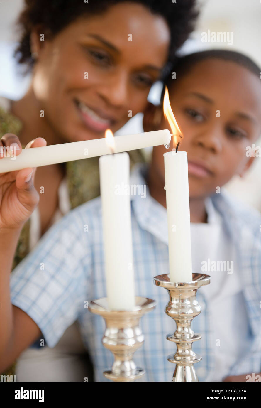 Nero madre e figlio accendendo candele insieme Foto Stock