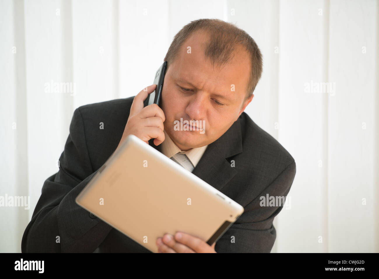 Giovane uomo calvo funziona con tablet pc e smart phone Foto Stock