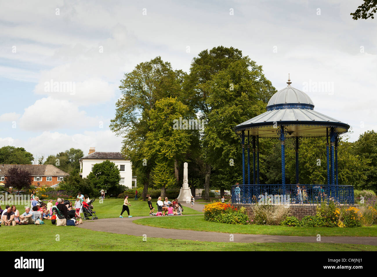 La famiglia godendo il sole intorno al palco per spettacoli presso la War Memorial Park a Romsey Foto Stock