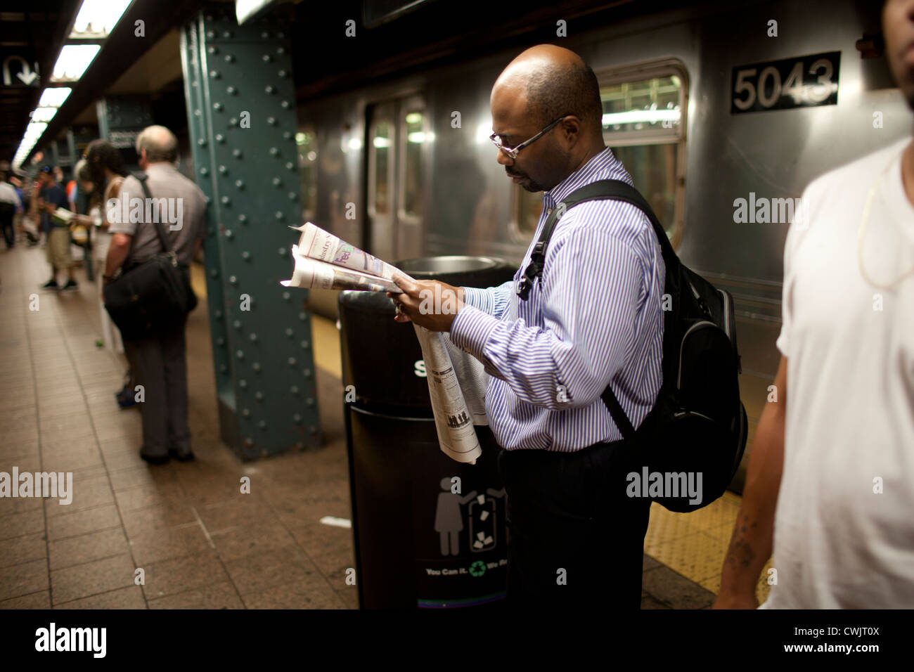 La gente in attesa di un treno su una metropolitana di New York la piattaforma. Il 2011 feriale medio alla metropolitana ridership è di 5,3 milioni di euro. Foto Stock