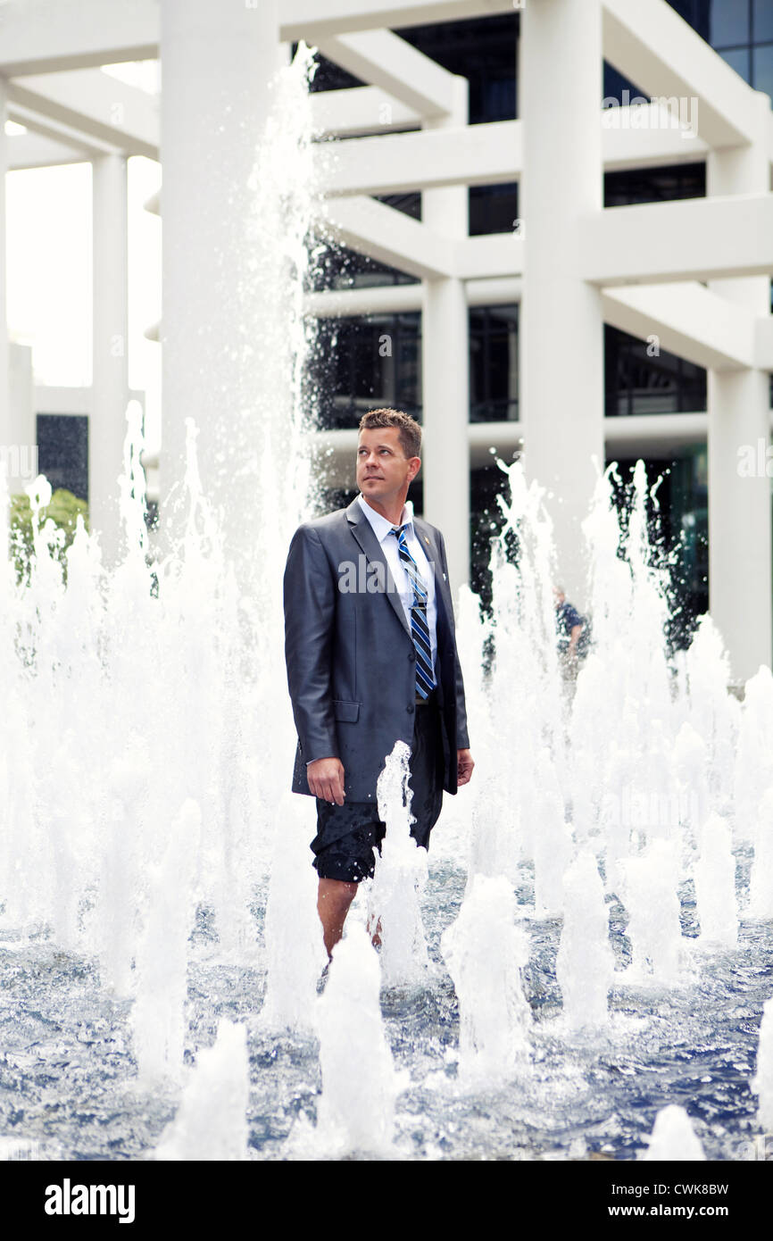 Imprenditore caucasico in piedi nella fontana Foto Stock
