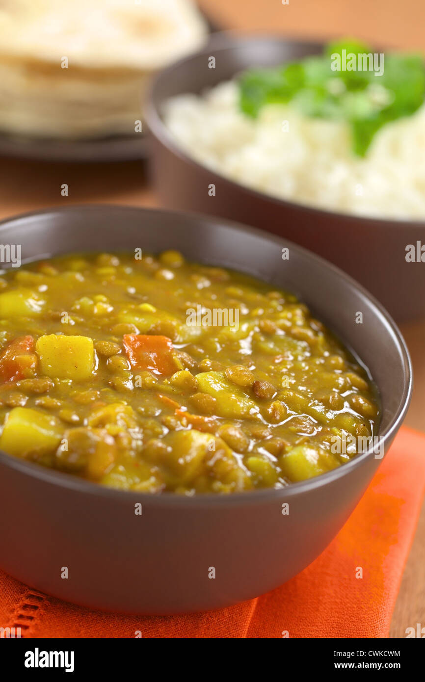 Ciotola di indiano piccante dal (lenticchia) curry preparato con la carota e la patata, riso e chapati flatbread nella parte posteriore Foto Stock