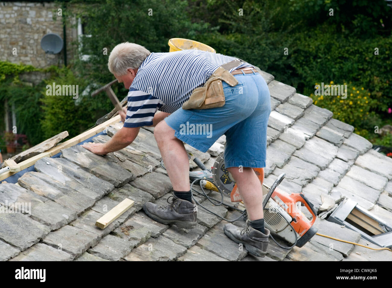 Un artigiano locale sostituzione tegole sul tetto del cottage tradizionale Foto Stock
