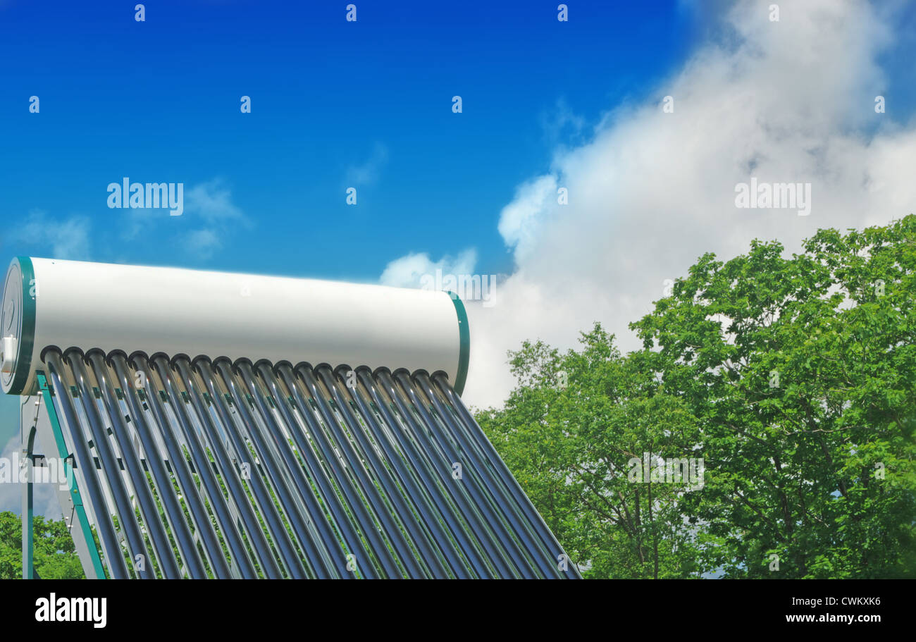 Riscaldamento di acqua solare sistema sul tetto di una casa su uno sfondo di cielo blu e verde della foresta Foto Stock