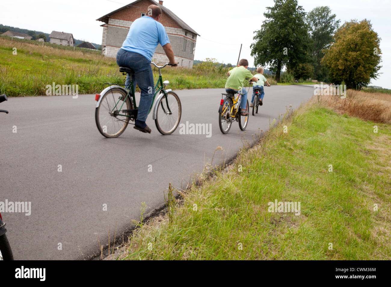 Papà polacco con due figli in bicicletta scendendo su strada di campagna. Zawady Polonia centrale Foto Stock