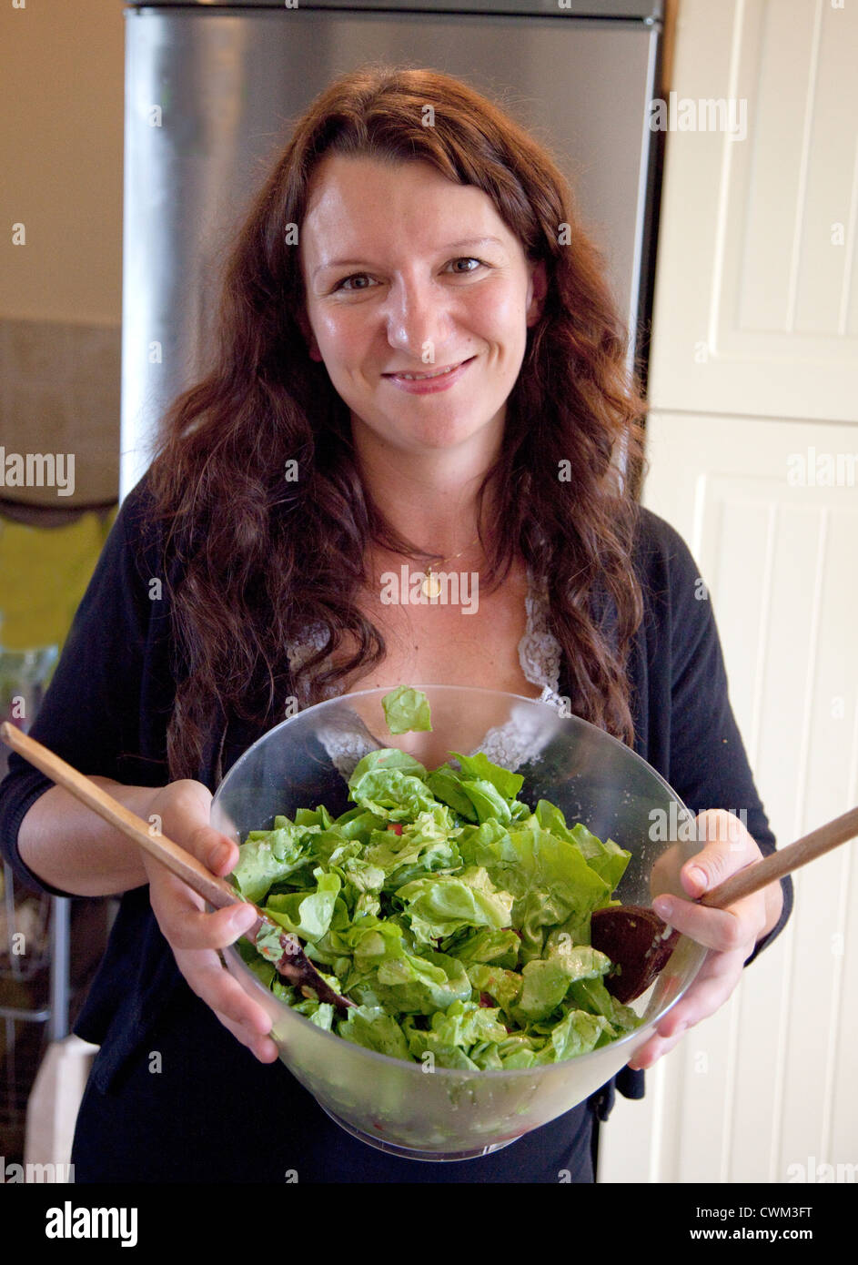 Felice donna polacca età 32 con in mano un bicchiere di intestino insalata di verdure fresche nella sua cucina. Zawady Polonia centrale Foto Stock
