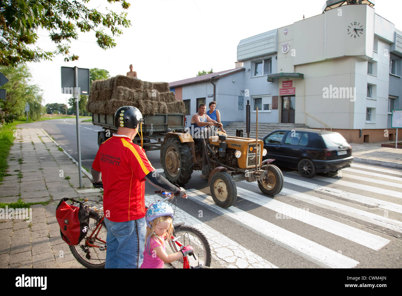 Azienda agricola polacca famiglia portando un carico di fieno in città mentre i ciclisti attendere per loro di passare. Rzeczyca Polonia centrale Foto Stock