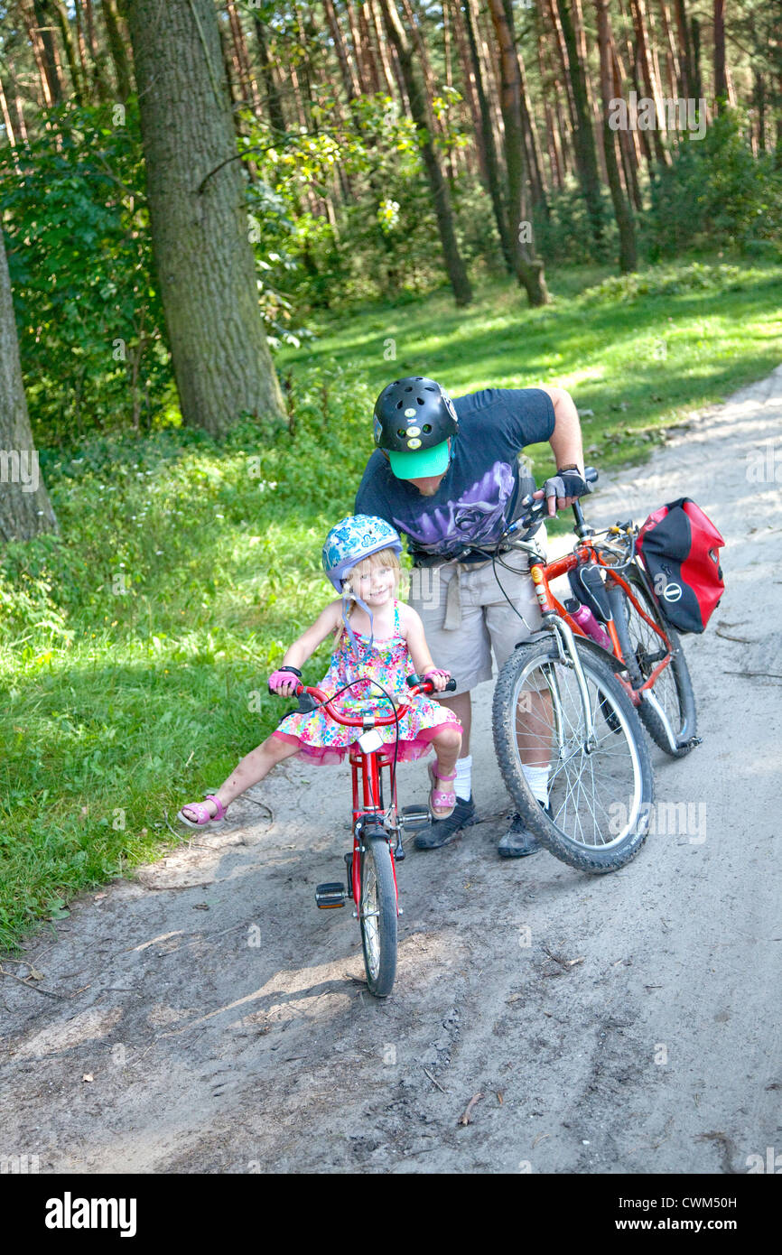 Papà dando inizio alla figlia di bilanciamento sulla bicicletta polacco della foresta nazionale di registrazione età trail 4 e 37. Zawady Polonia centrale Foto Stock