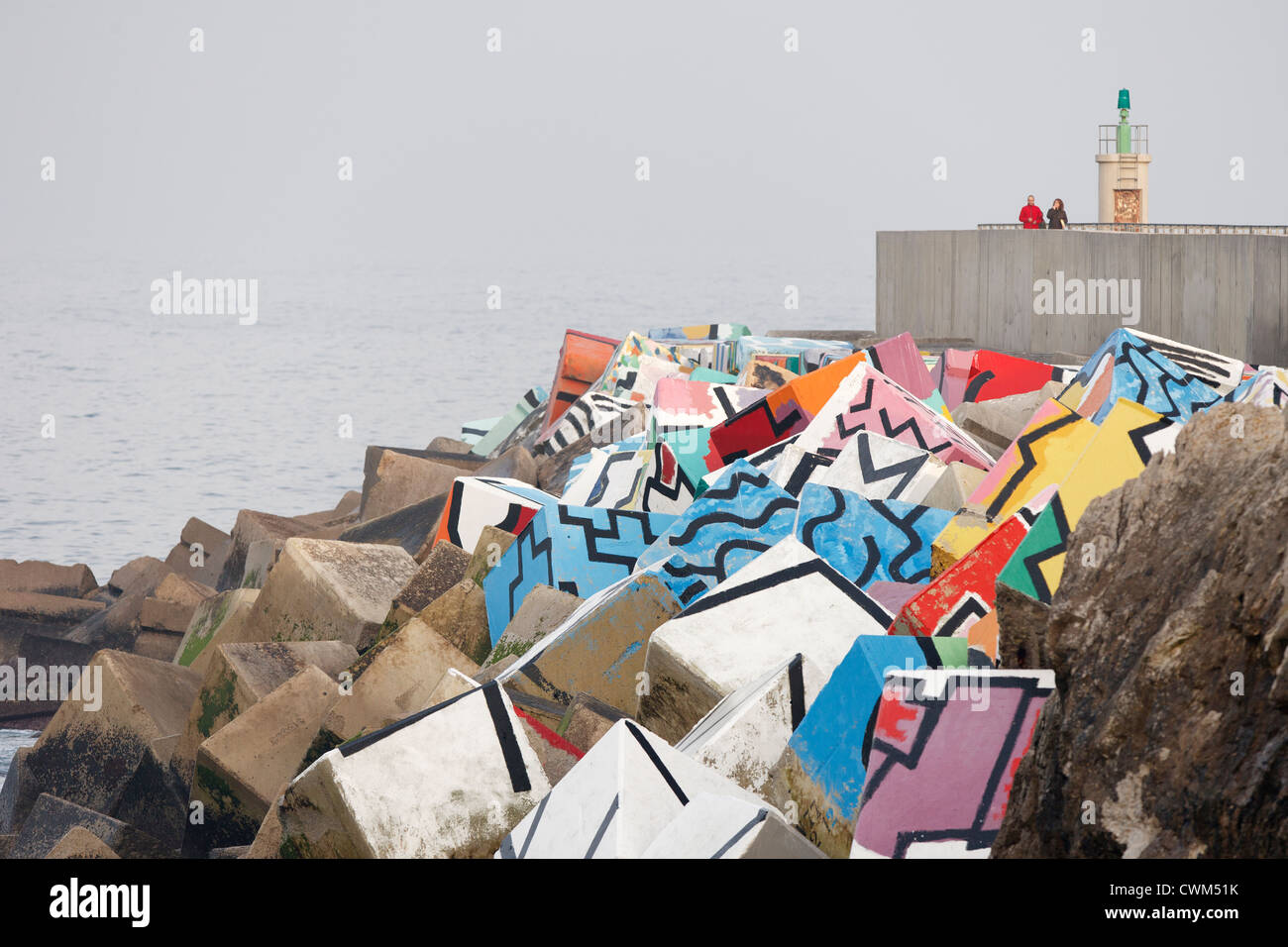 Porto di Llanes. Agustín Ibarrola ha dipinto cubi di calcestruzzo della parete del porto in sorprendenti colori e disegni esilaranti. Foto Stock