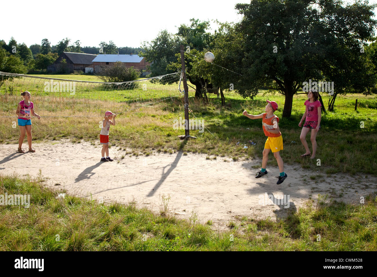 Il polacco gli adolescenti e i bambini giocando a pallavolo su village arcade style corte. Mala Wola Polonia centrale Foto Stock