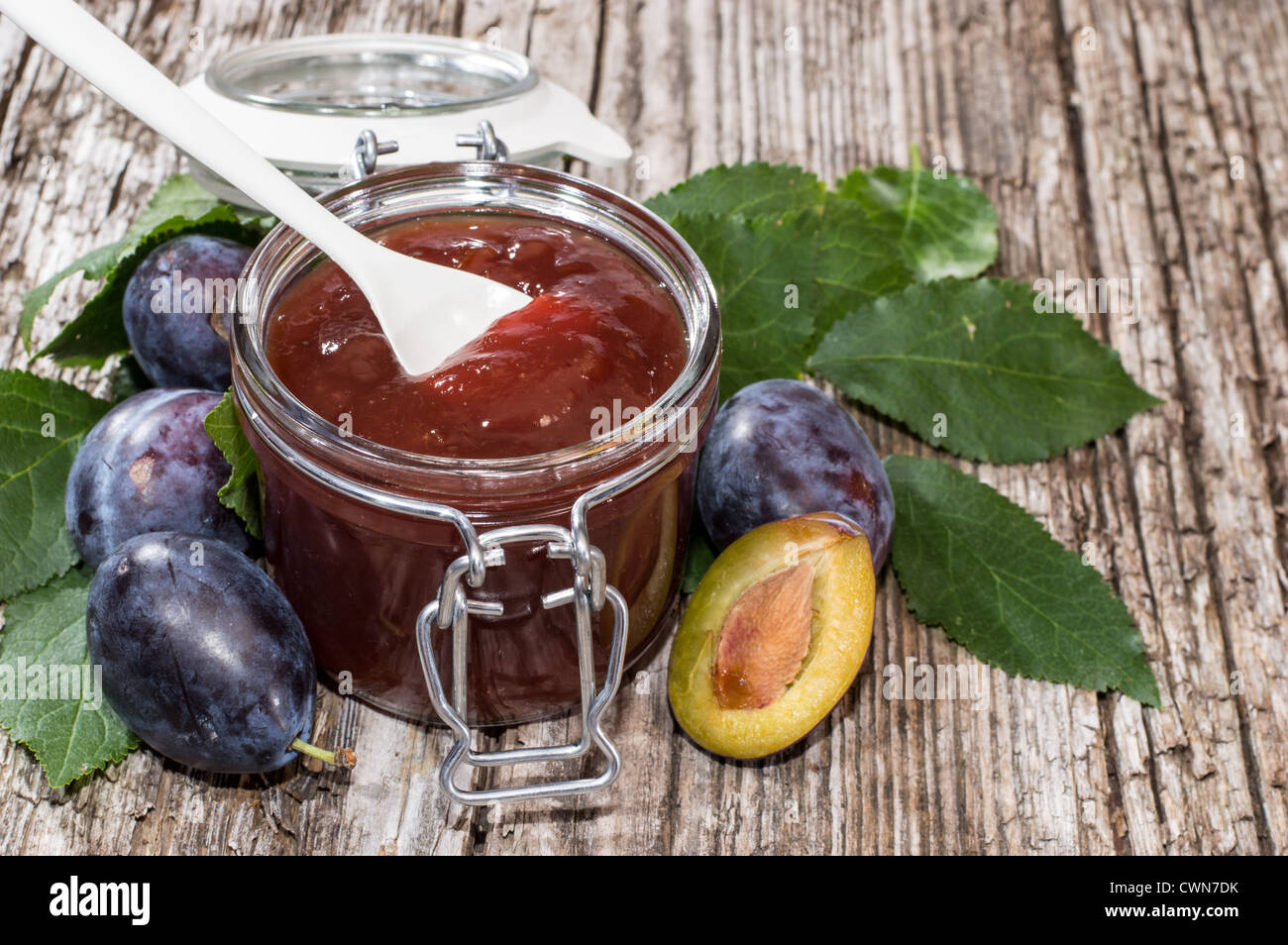 Vetro con marmellata di prugne su un vecchio tavolo in legno Foto Stock