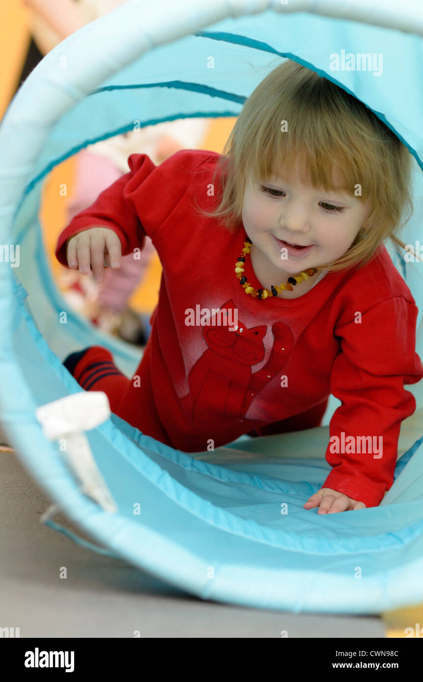 Bambina strisciando attraverso il tunnel Foto Stock