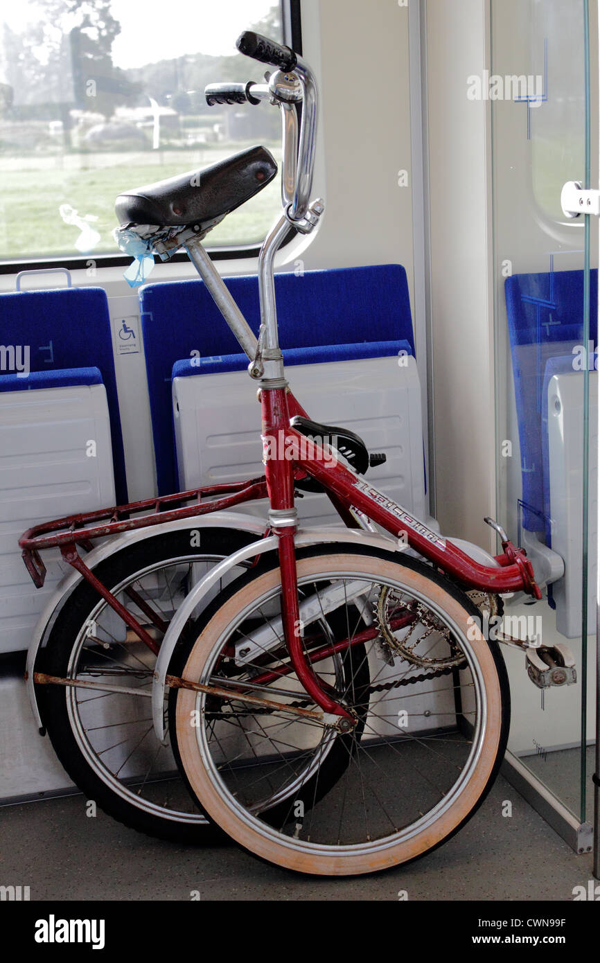 Red vecchia bicicletta pieghevole in un treno Olandese Foto stock - Alamy