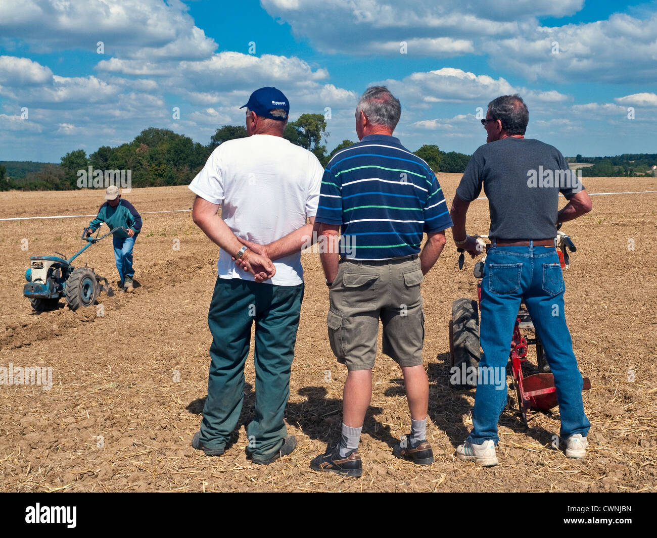 Tre gli agricoltori a guardare concorrente alla partita di aratura - sud-Touraine, Francia. Foto Stock