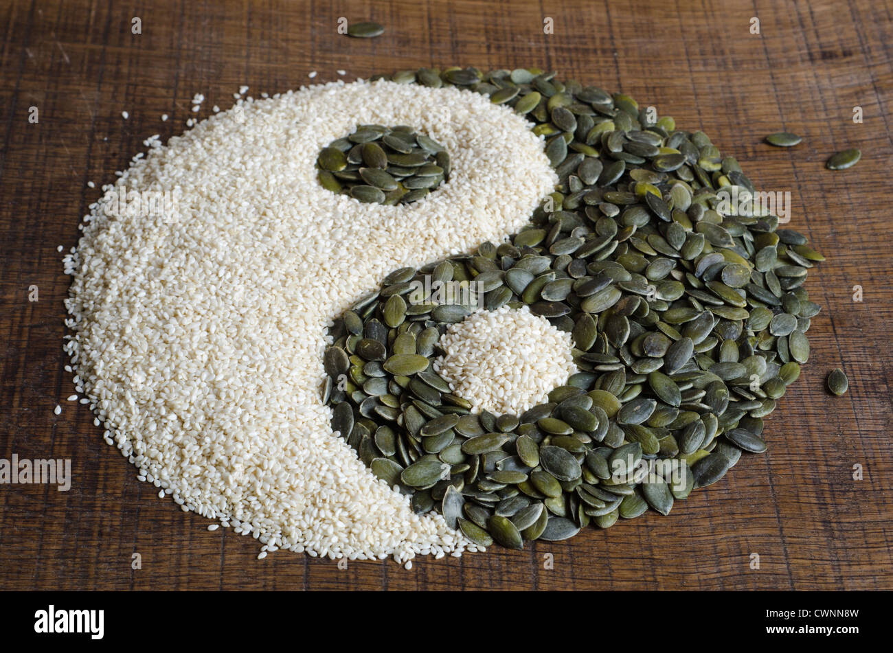 Yin Yang creati al di fuori di semi di zucca e i semi di sesamo al buio su un superficie di legno Foto Stock