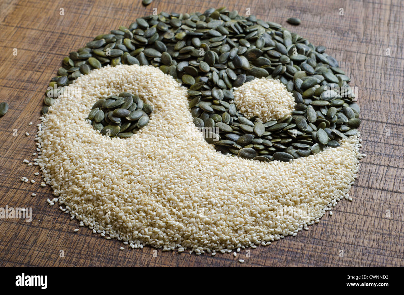 Yin Yang creati al di fuori di semi di zucca e i semi di sesamo al buio su un superficie di legno Foto Stock