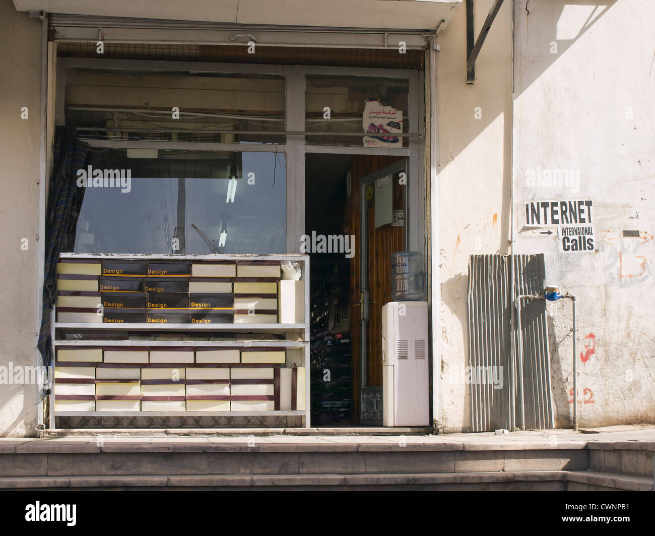Facciata di un negozio di scarpe in una stradina in Aqaba Giordania con le scatole di scarpe e un segno che mostra il modo in cui per le chiamate telefoniche tramite Internet Foto Stock