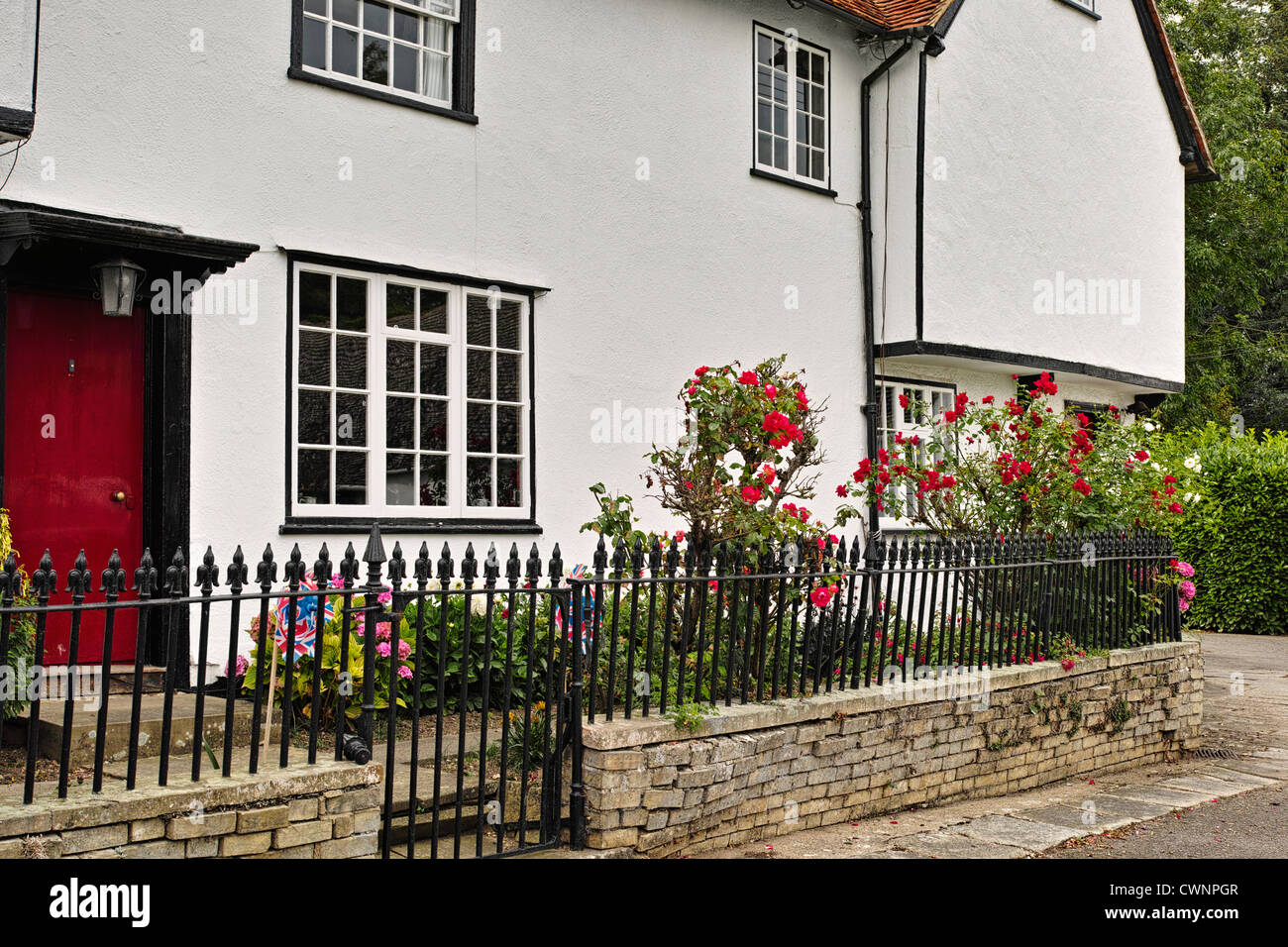 Vecchia casa con porta rossa e le rose nel villaggio di Lindsell nei pressi di Great Dunmow Foto Stock