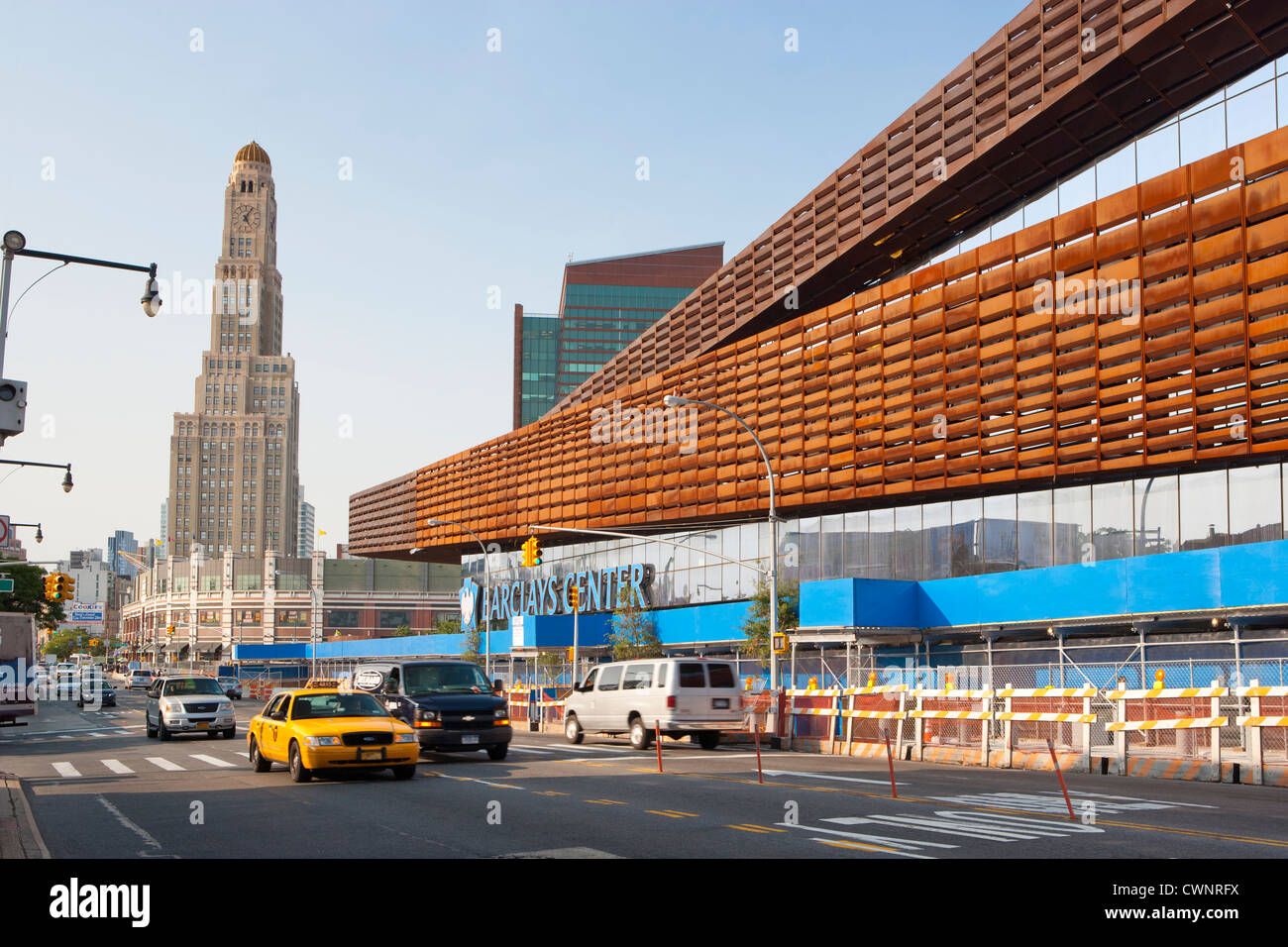 New York City Taxi drives passa il nuovo Barclays Center home di Brooklyn Nets Sports Arena e dalla sala da concerto. Il Landmark Williamsburgh Savings Bank Tower in background, Brooklyn, NY, STATI UNITI D'AMERICA Foto Stock